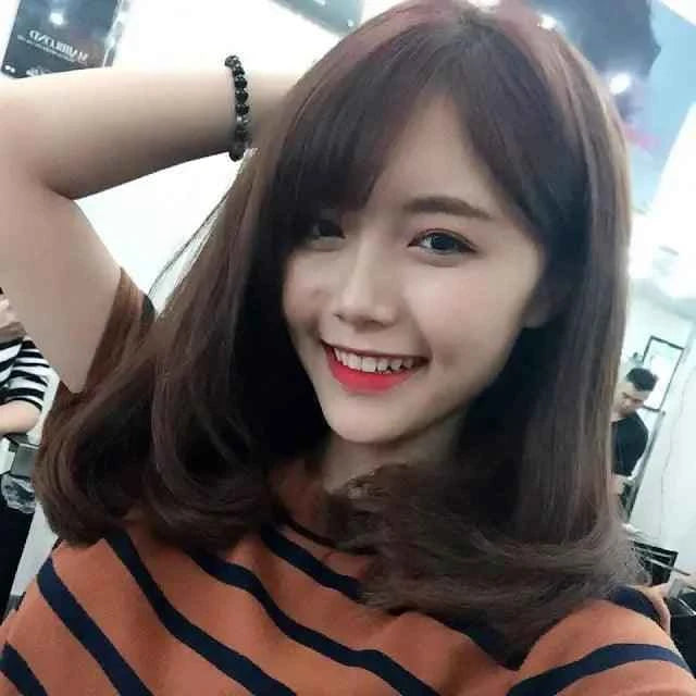 Smiling woman with straight, medium-length brown hair in a striped shirt at a salon